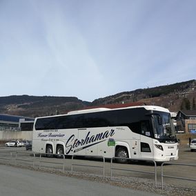 Hvit turbuss parkert foran skianlegg